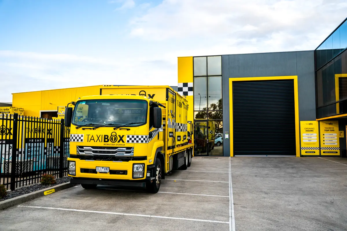 A yellow TAXIBOX truck outside the Braeside storage facility