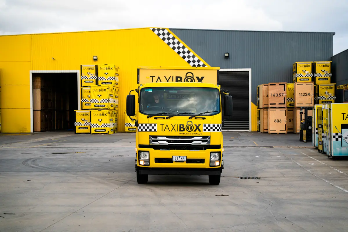 A yellow TAXIBOX truck and TAXIBOX boxes outside the Braeside storage facility